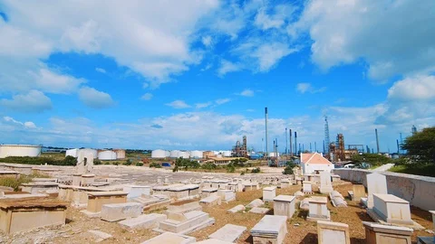 Wide angle shot of an empty cemetery in Curacao with a large industrial Stock Footage 99589211