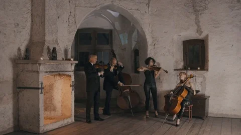 Wide angle shot of a string quartet playing in a medieval style castle Stock Footage 92543126