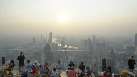 Wide-angle shot of tourists sitting at a rooftop bar overlooking downtown Video stock 301793359