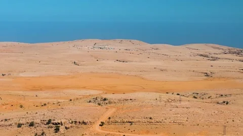 A wide angle shot of a vast, arid desert landscape with gentle hills under a cle Stock Footage 318642959