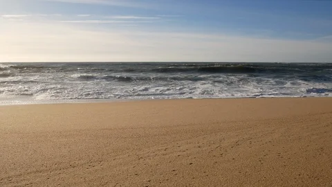Wide angle shot of waves breaking on empty, sandy beach on sunny day Stock Footage