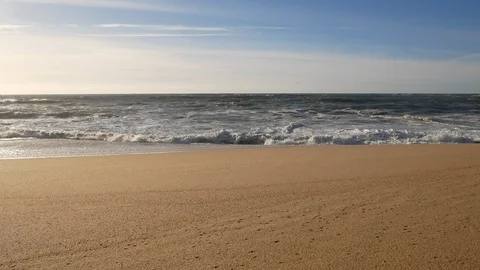Wide angle, slow pan up from sandy beach to ocean waves breaking on the shore Stock Footage 103286599