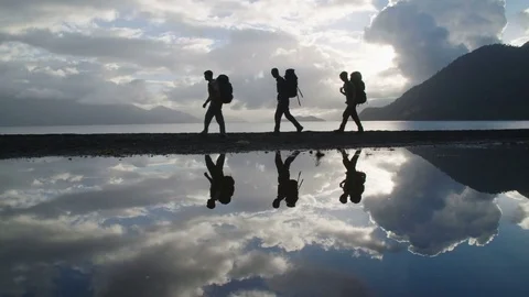 Wide Angle Tracking Shot Of Three Men Backpacking Past Their Reflections Stock Footage 70453106