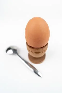 Wide angle vertical shot of hen egg in old wooden egg stand with metal spoon Stock Photos