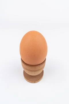 Wide angle vertical shot of hen egg in old wooden egg stand isolated on white Stock Photos