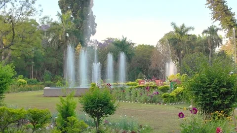 Wide Angle View Of Active Water Fountains And Blooming Flower Beds In Lush .. Stock Footage 342399936