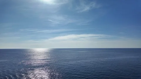 Wide-Angle View of Calm Blue Ocean under Clear Sky with the Sun Reflecting on th Stock Footage 283547885