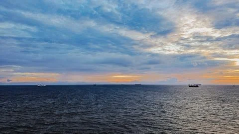 Wide angle view of commercial cargo ships floating on sea horizon under col.. Foto stock