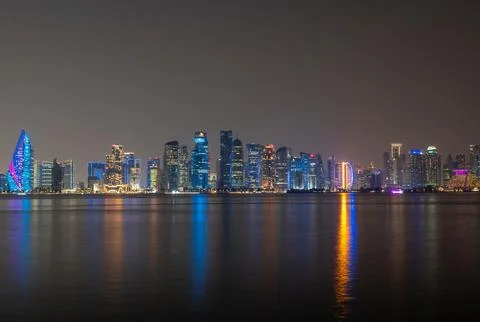 Wide angle view of Doha's modern skyscrapers reflecting on the calm sea. Photos