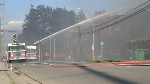 Wide angle view of a firetruck putting out a fire at a residential building. Stock Footage 135435378