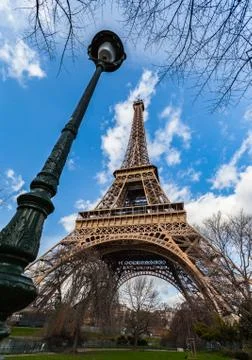 Wide angle view of iconic Eiffel tower with dramatic cloudy blue sky Stock Photos