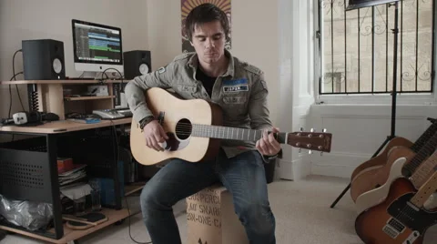 Wide angle view of man playing acoustic guitar in his music studio Stock Footage 50245458