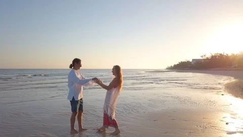Wide angle view of mature couple embracing and dancing on the beach at sunrise. Stock Footage 104012287