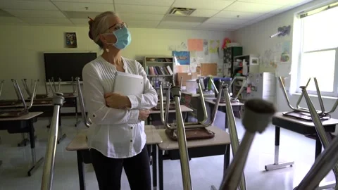 Wide angle view moving left of sad teacher wearing a medical face mask in an Stock Footage 137646452