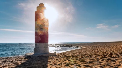 Wide angle view over beach in summer. Sun behind lighthouse with lens flare Stock Footage 108516715