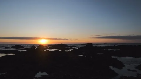Wide angle view over rocky shore at sunset with vivid colorful orange sky Video stock 115757393