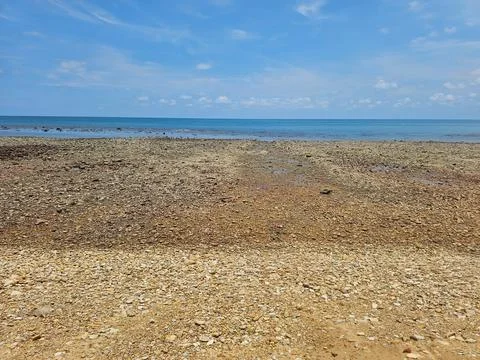Wide Angle View of Pebble Stone Beach and Calm Blue Sea Under Clear Sky Stock Photos