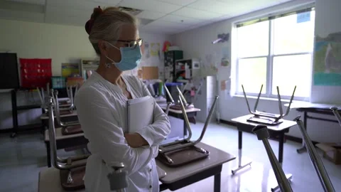 Wide angle view of sad teacher wearing a medical face mask in an empty classroom 스톡 동영상 137645743