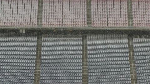 Wide angle view of snow falling on empty seats in stadium Stock Footage 104774042
