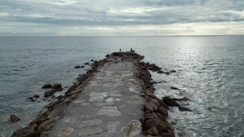 Wide angle view of stone jetty extending into ocean under overcast sky Video stock 327672200
