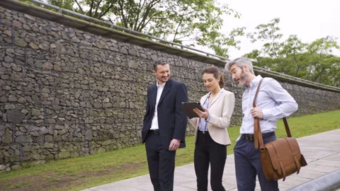 Wide angle view of three coworkers looking at digital tablet screen while Stock Footage 277973972