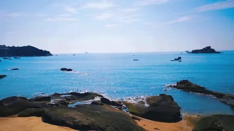 Wide angle view of a tranquil blue ocean coastline with rocky shore and boats Stock Footage 342014555