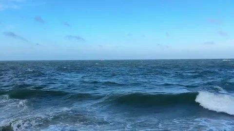 Wide angle view of the vast blue ocean with gentle waves and a clear sky on a Vidéo 334163310