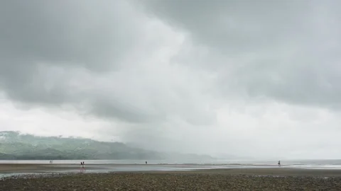 Wide-angle view of a vast, tranquil beach with small figures of people walking Видео 336056159