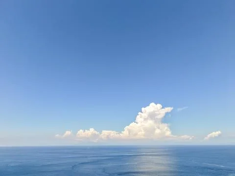 Wide Angle View of White Cumulus Clouds over Calm Blue Ocean Horizon Foto stock