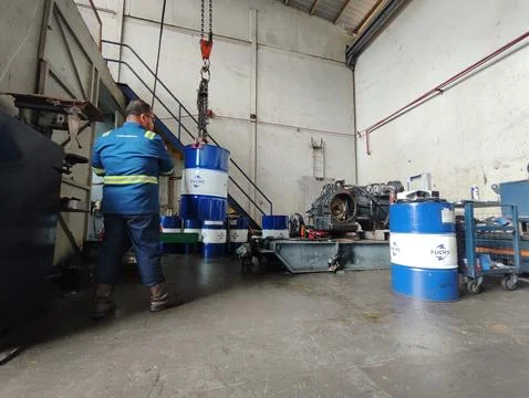 Wide angle view of worker lifting oil barrel Stock Photos