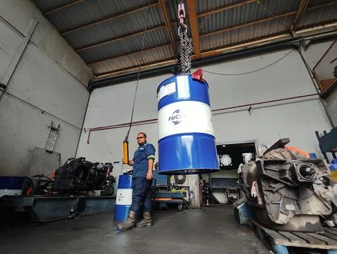 Wide angle view of worker lifting oil barrel Foto stock
