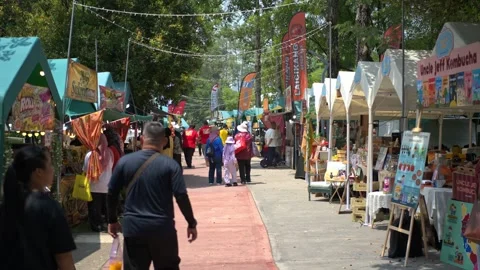 Wide angle of visitors walking through an outdoor food and craft street market Stock Footage 346349967