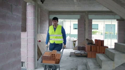Wide Angle of Worker Pushing Wheelbarrow in Construction Site, Full Room View Stock Footage 299268298
