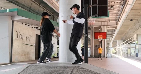 Wide angle of young man and woman doing freestyle street dancing with basketball Stock Footage 106377797