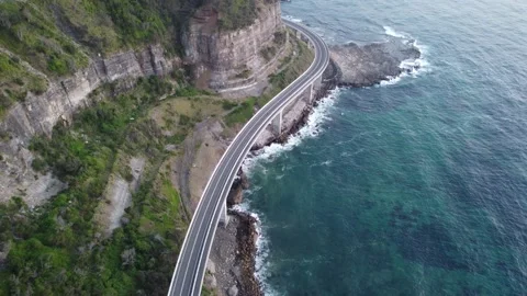 Wide angled moving out drone shot of a bridge with grassland and waves Stock Footage 143620124