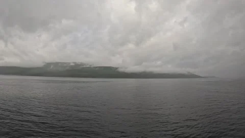 Wide boat tracking shot across open fjord towards fog covered mountain coastline Stock-Footage 341814636