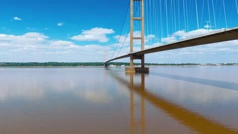 Wide bridge spans calm river under bright blue sky Vidéo 343519830