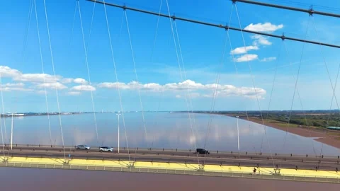 Wide bridge spans calm river under bright blue sky Видео 343539082