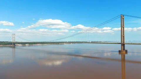 Wide bridge spans muddy river under clear blue sky Vidéo 343544716