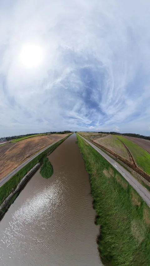 Wide canal flows through green fields under a bright sky Stock Footage 345408360