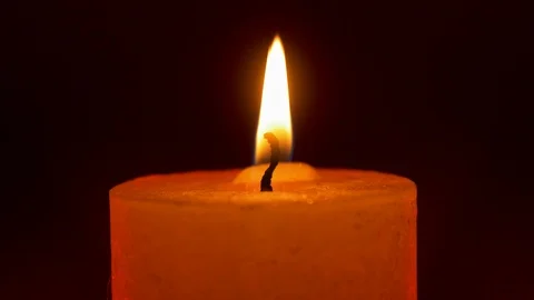 Wide candle flame on black background with red rim light Stock Footage 122867823