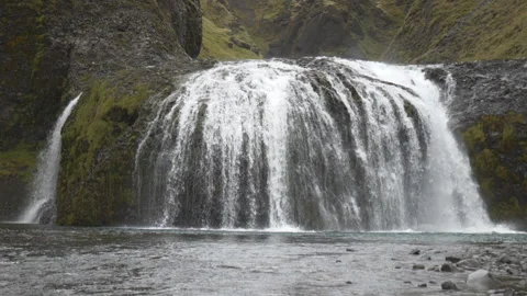 A wide, cascading waterfall rushing down over a mossy rock face. Stock Footage 335960018