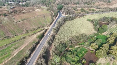 Wide cinematic aerial of a curving mountain road showcasing heavy vehicles Stock Footage 336033853