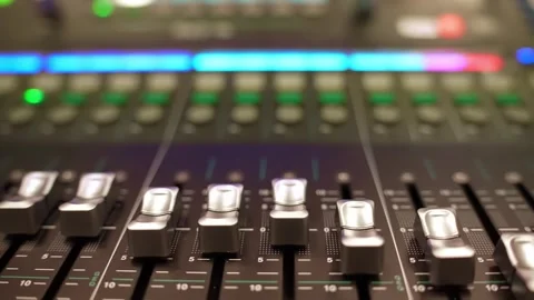 Wide close-up of an audio desk with multiple channel faders and glowing LED Stockbeeldmateriaal 328338661