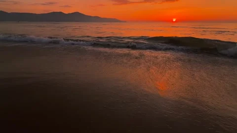 Wide Close up of Waves on the sand and Picturesque Coastal Sunset with Mountain Stock Footage 343595051
