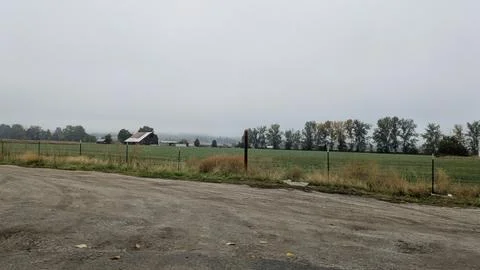 Wide crop fields and a distant farm building unfold Stock Photos