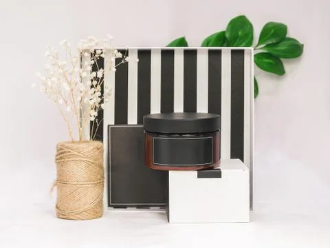 A wide dark jar for cosmetic products is standing on a cardboard box Stock Photos