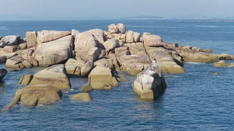 Wide daylight view of large granite rocks emerging from the blue Atlantic Ocean Stock Footage 346688806