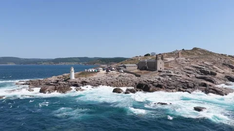 Wide daytime view of Faro de Muxia lighthouse on a rugged rocky peninsula, with Stock Footage 346695027