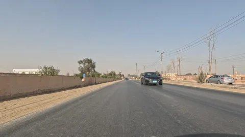 Wide desert horizons appear while driving along Cairo Fayoum Desert Road highway Stock Footage 329840779